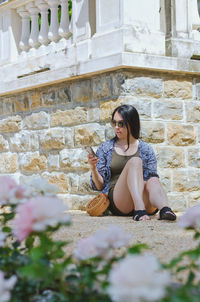 Portrait of young woman sitting on wall