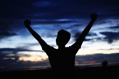 Rear view of silhouette person standing in front of sea during sunset