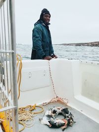 Portrait of man fishing in sea against sky