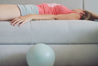 Midsection of woman lying on sofa at home
