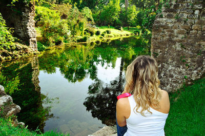 Rear view of woman looking at lake against trees