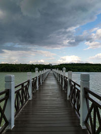 View of wooden bridge over water against sky