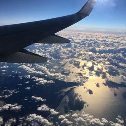 Aerial view of airplane wing over landscape against sky