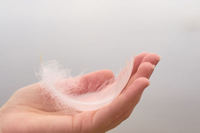 Close-up of hand holding crystal against white background