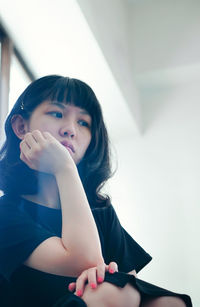 Portrait of young woman looking away while sitting at home