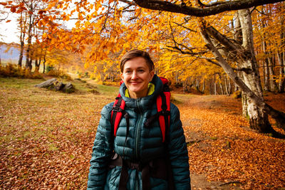 Portrait of smiling young woman in forest during autumn