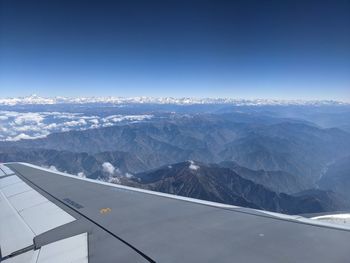 Aerial view of snowcapped mountains against blue sky