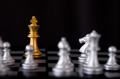 Close-up of game pieces on chess board against black background