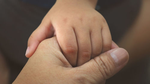 Close-up of mother and child with holding hands