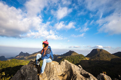 People on rock by mountain against sky