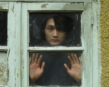 Close-up portrait of man looking through window