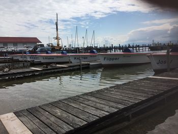 Boats moored at harbor against sky