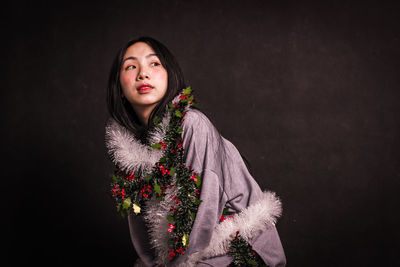 Beautiful young woman looking away against black background