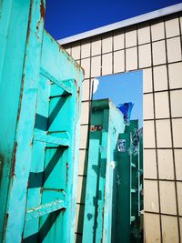 Low angle view of graffiti on building against blue sky