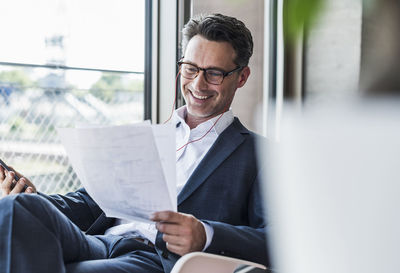 Smiling businessman on the phone reading documents