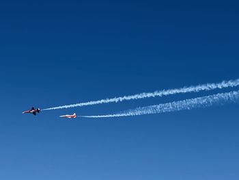 Low angle view of airplane flying against clear blue sky