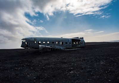 Abandoned airplane on land against sky