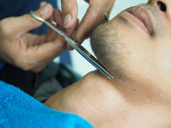 Cropped hands of barber cutting mid adult man beard in shop
