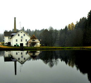 Reflection of houses in lake against clear sky