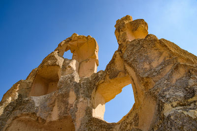 Low angle view of rock formation against clear blue sky