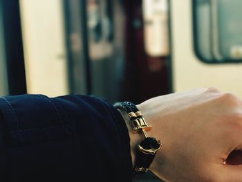 Cropped hand of person wearing bracelet by train