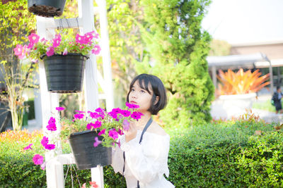 Young woman standing by flower pot in park