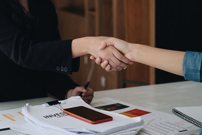 Midsection of business colleagues shaking hands in office