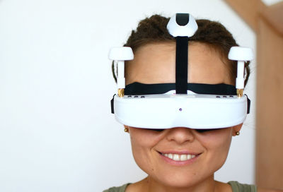Close-up of smiling woman wearing virtual reality simulator against wall