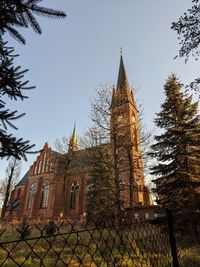 Low angle view of trees and building against sky