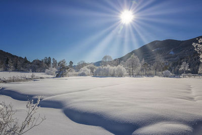 Scenic view of snow covered mountains against bright sun