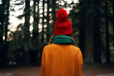 Rear view of woman standing by tree in forest