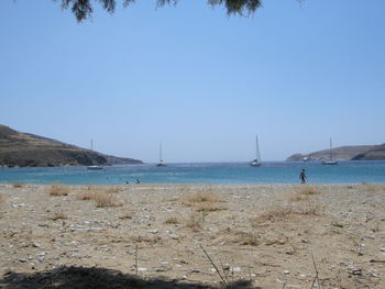 Boats in calm sea against clear blue sky