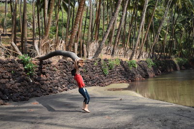 Full length of woman standing on riverbank in forest
