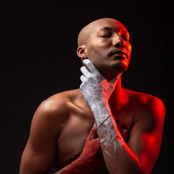 Young man looking away against black background