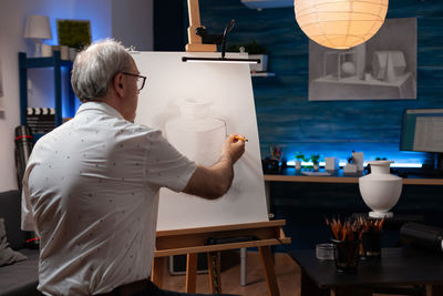 Rear view of senior man painting at home