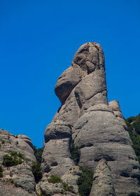 Low angle view of rock formation against clear blue sky