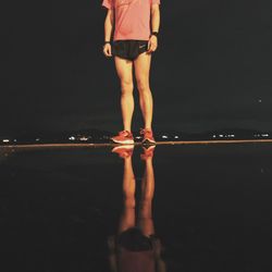 Woman standing on wet street at night