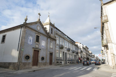 Cars on road by buildings against sky