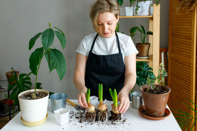 Portrait of smiling woman holding potted plant on table