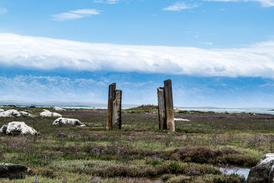 Poles on field against cloudy sky