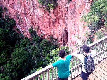 Rear view of people standing on footbridge