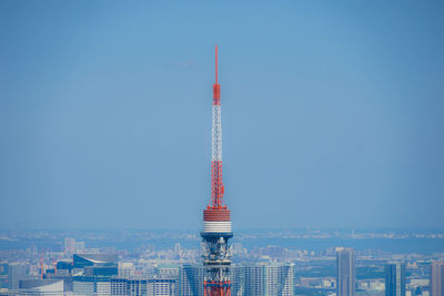 Communications tower in city against clear blue sky
