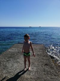 Boy on beach against clear sky