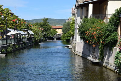 River amidst houses and buildings against sky