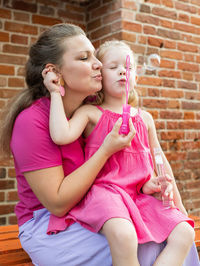 Mother and daughter sitting on sofa at home