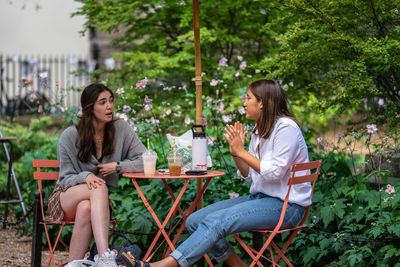 Woman sitting on table at outdoor cafe against plants