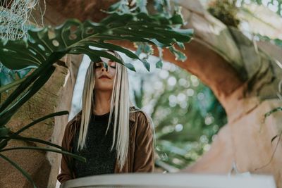 Low angle view of young woman with eyes closed standing outdoors