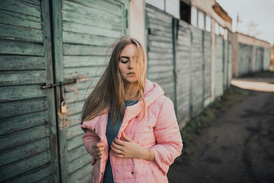 Young blonde girl dressed fashion pink jacket. old azure cerulean fence.  women magazines