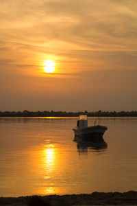 Silhouette boat in sea against orange sky