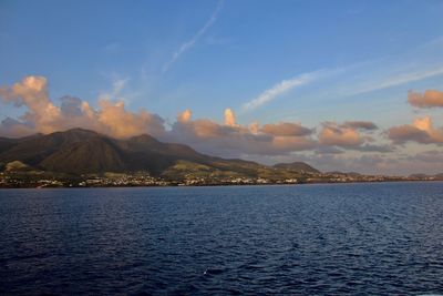 Scenic view of sea by mountain against sky